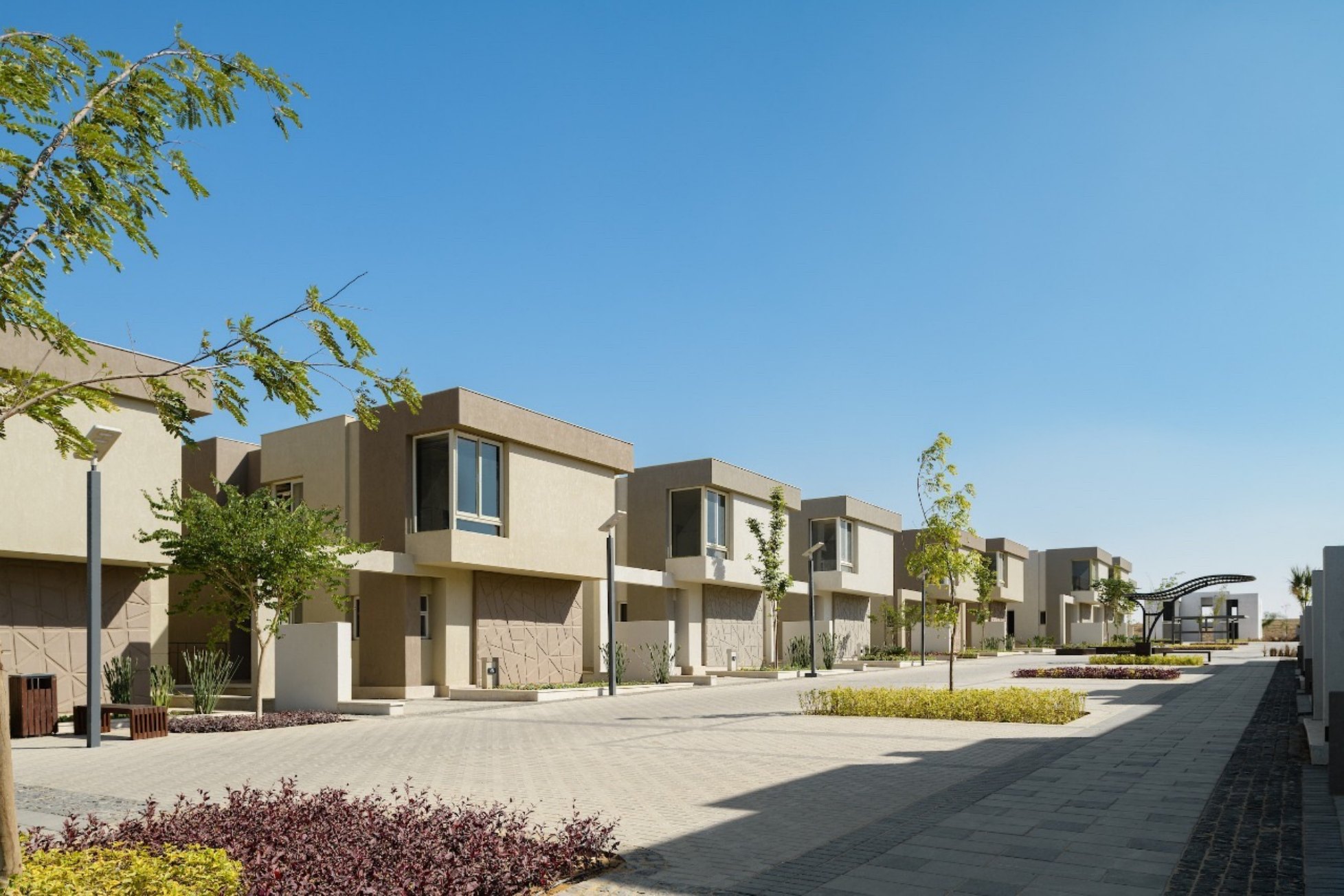 Villa street — A paved street lined with two-storey villas and planters.