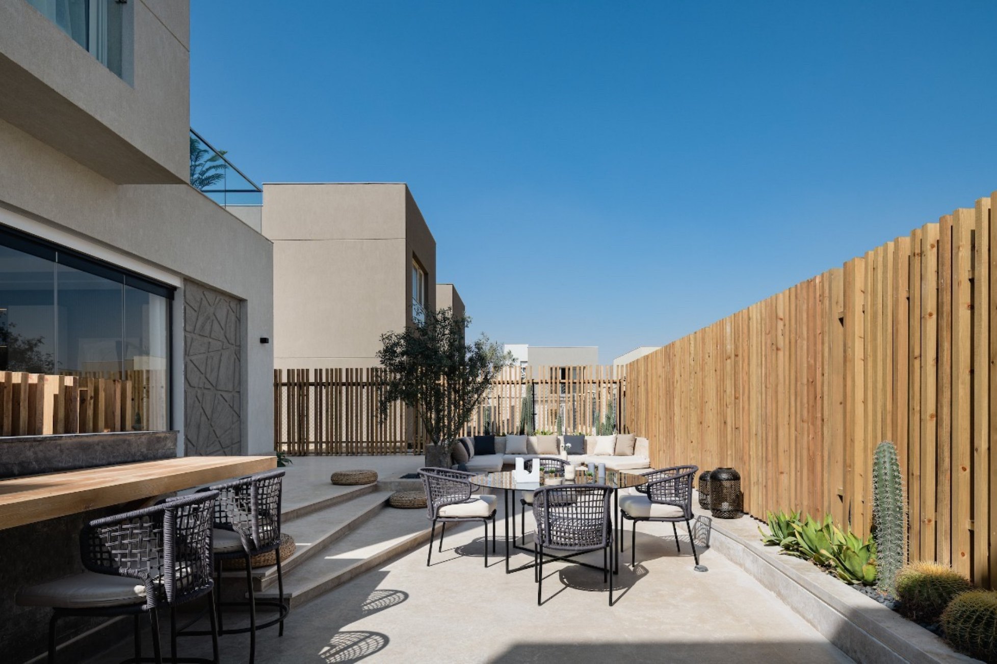 Outdoor lounge — A private villa garden with a bar counter, dining table and sofa.