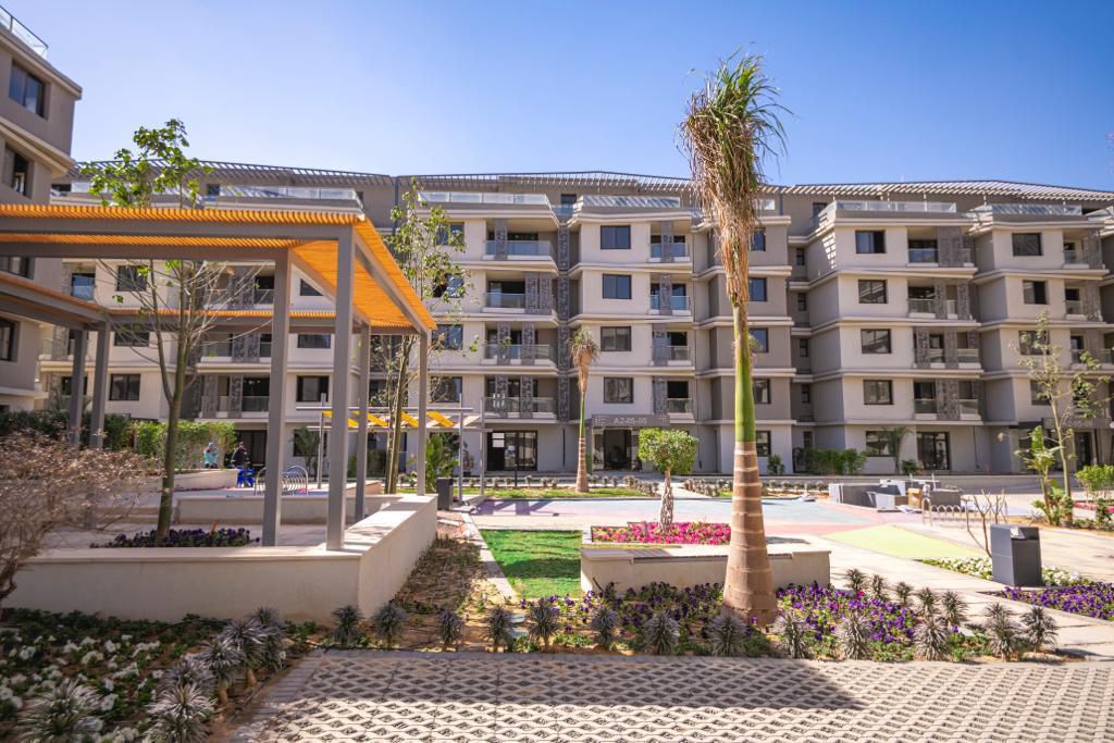 Courtyard pergola — A shaded pergola and garden beds between apartment blocks.