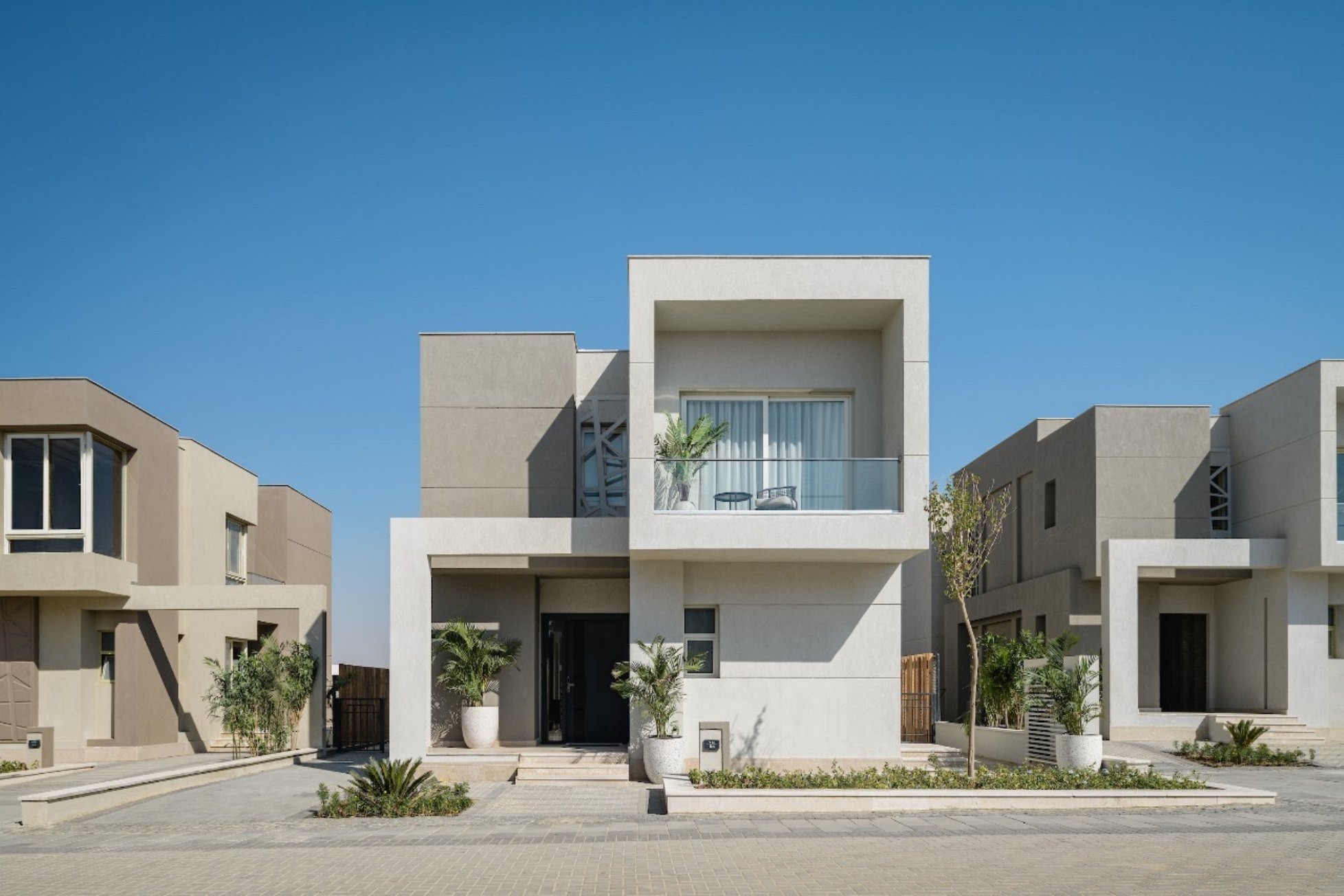 Villa front — A villa entrance and balcony with potted planting.