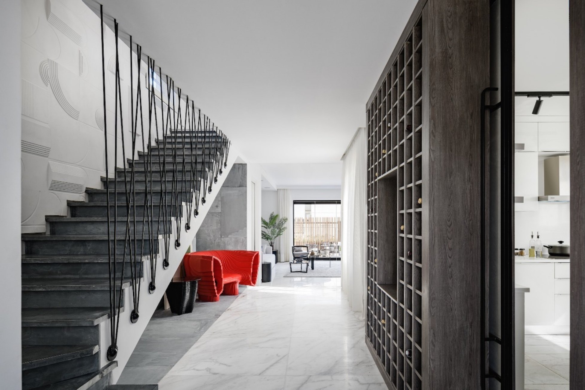 Villa foyer — Entrance hall with a staircase, grid shelf wall and open living beyond.